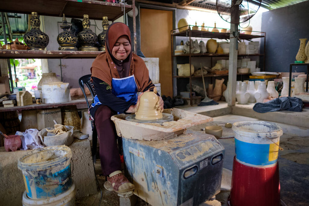 Τοπική γυναίκα επιδεικνύει για την κατασκευή παραδοσιακό πήλινο βάζο που ονομάζεται Labu Sayong ή Essence Jar του Sayong μέσα εργαστήριο στην Κουάλα Κανγκσάρ, Περάκ, Μαλαισία. Παραδοσιακή κεραμική έννοια. - Φωτογραφία, εικόνα