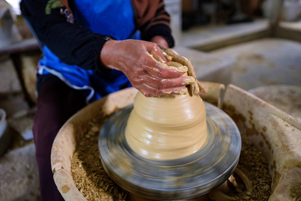 Closeup of Local woman demonstrates on making traditional clay jar called Labu Sayong or Essence Jar of Sayong inside workshop in Kuala Kangsar, Perak, Malaysia. Traditional Pottery concept. - Photo, Image