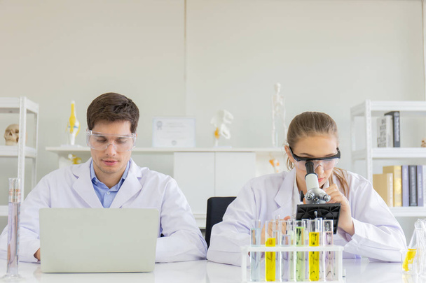 concept of a healthcare researcher, a researcher working in a life science lab, a young research scientist and a male supervisor preparing and analyzing microscopic slides in a research laboratory - Фото, изображение
