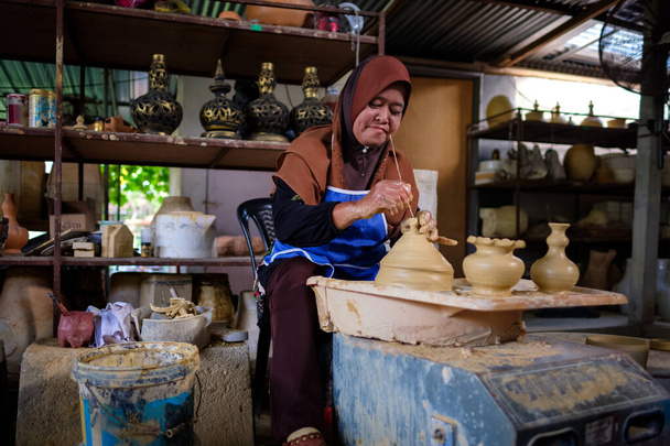 Paikallinen nainen osoittaa tehdä perinteisiä savi purkki nimeltään Labu Sayong tai Essence Jar Sayong sisällä työpaja Kuala Kangsar, Perak, Malesia. Perinteinen keramiikka käsite
. - Valokuva, kuva