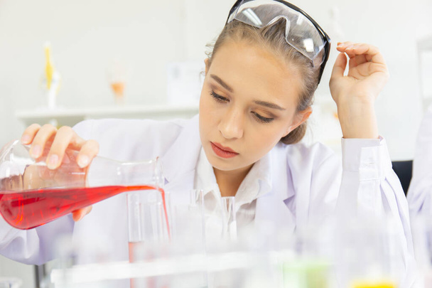 A beautiful female scientist is operating in a science lab with various equipment in the lab. - Foto, Bild