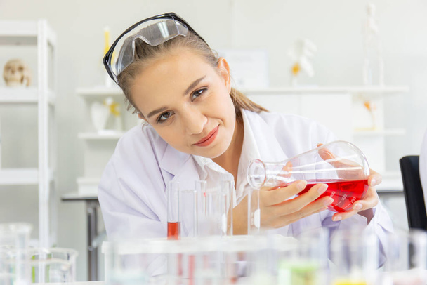 Een mooie vrouwelijke wetenschapper opereert in een wetenschappelijk lab met verschillende apparatuur in het lab. - Foto, afbeelding