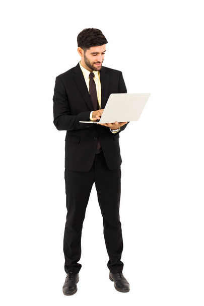 Ein gutaussehender junger Mann steht auf einem Tablet isoliert auf weißem Hintergrund, - Foto, Bild