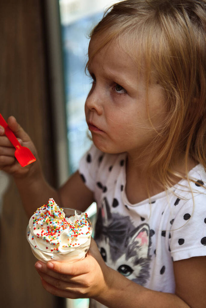 Little girl eating ice cream with sprinkles - Zdjęcie, obraz