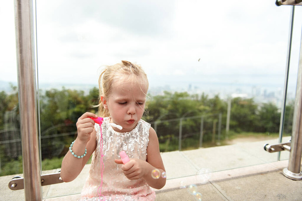 Girl making soap bubbles on top of the mountains in a cafe - Valokuva, kuva