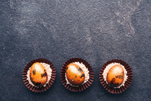 Bright orange Easter quail eggs on a black background, top view. Easter background. - 写真・画像