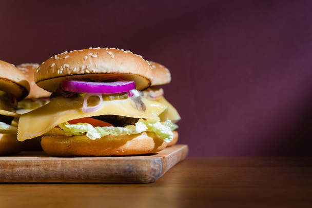 Hausgemachte Cheeseburger auf einem Holztablett. - Foto, Bild
