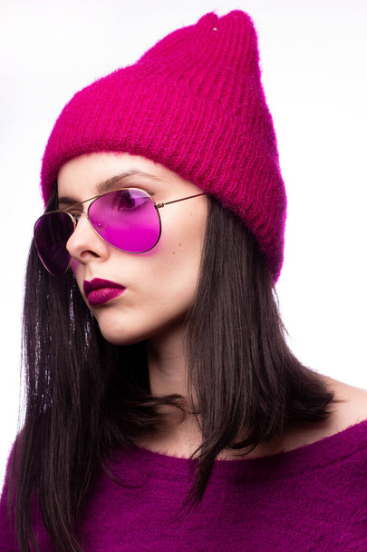 girl in a purple sweater, purple glasses with purple lipstick on the lips in a pink hat - Фото, изображение