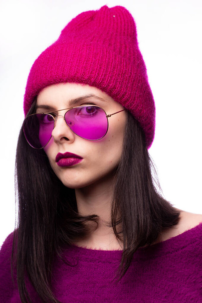 girl in a purple sweater, purple glasses with purple lipstick on the lips in a pink hat - Foto, afbeelding