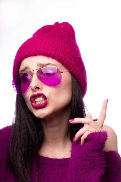 girl in a purple sweater, purple glasses with purple lipstick on the lips in a pink hat - Photo, image