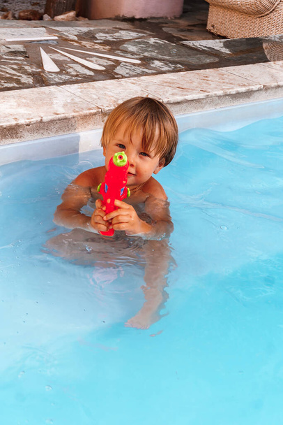 chlapec hraje s vodní pistolí v bazénu - Fotografie, Obrázek