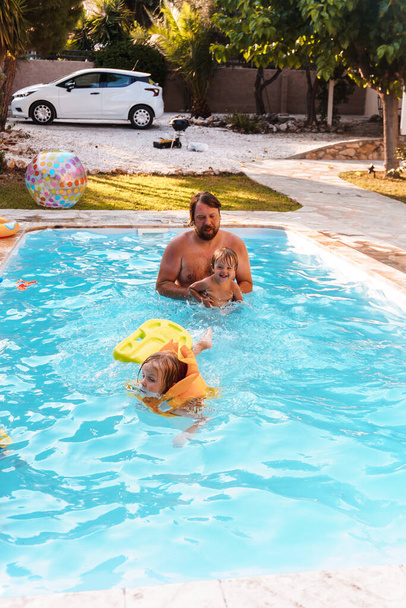 息子と一緒に家の近くのプールで泳いでいるお父さん - 写真・画像