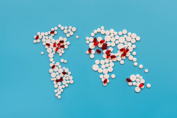 Covid-19. La forma della mappa del mondo fa da pillole bianche con pillole rosse come aree infettate da virus su sfondo blu. Influenza, concetto di malattia
 - Foto, immagini