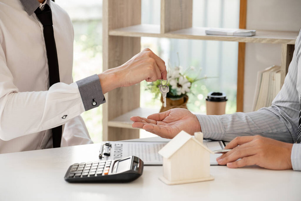 Real estate agent broker hand over the house key to the new owner after completing the signing according to agreement renting a house and buy house insurance Home insurance concept. - Photo, Image