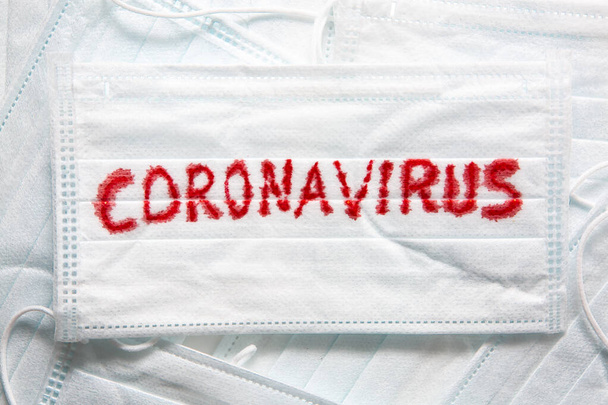 Concept of a coronavirus pandemic.Medical Disposable Face Mask with covid-19 printed on it. Covid-19 - Wuhan Novel Coronavirus pneumonia gets official name from WHO: COVID-19. Disposable breath filter face mask with earloop. - Fotó, kép