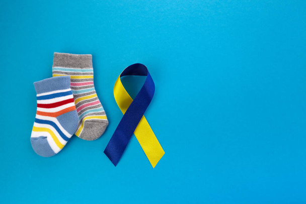 World Down syndrome day background. Down syndrome awareness concept. Socks and ribbon on blue background - Foto, Bild