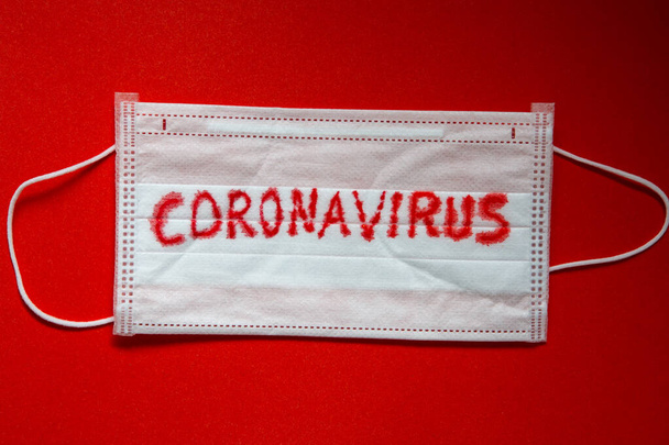 Fogalma a koronavírus világjárvány. Orvosi eldobható arc maszk covid-19 nyomtatott rajta. Covid-19 - A Wuhan Novel Coronavirus pneumonia hivatalos nevet kap a WHO-tól: COVID-19. eldobható lélegeztető szűrő arc maszk fülhurokkal. - Fotó, kép