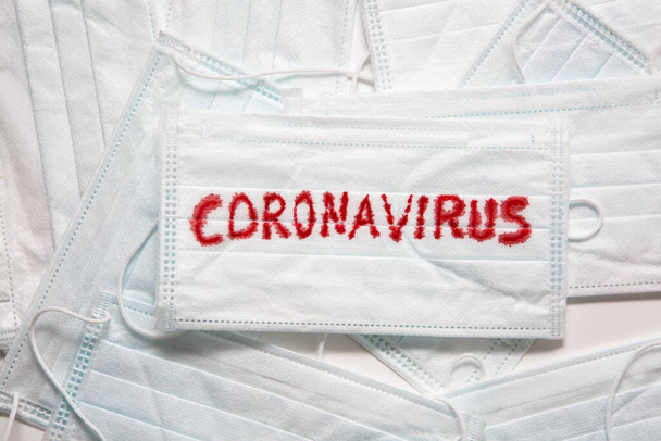 Concept of a coronavirus pandemic.Medical Disposable Face Mask with covid-19 printed on it. Covid-19 - Wuhan Novel Coronavirus pneumonia gets official name from WHO: COVID-19. Disposable breath filter face mask with earloop. - Foto, Imagem