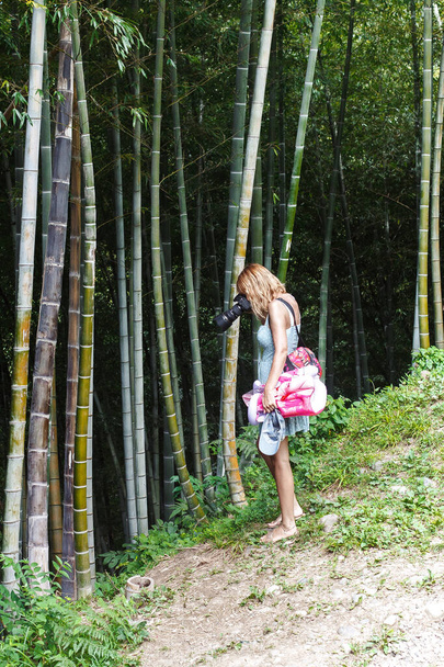 girl walking in a bamboo park with a camera - Foto, afbeelding