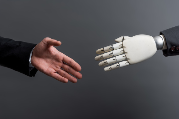 cropped view of businessman gesturing near robot isolated on grey, evolution concept  - Photo, Image