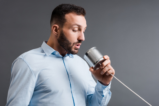 bearded man taking while holding tin can isolated on grey  - Photo, Image