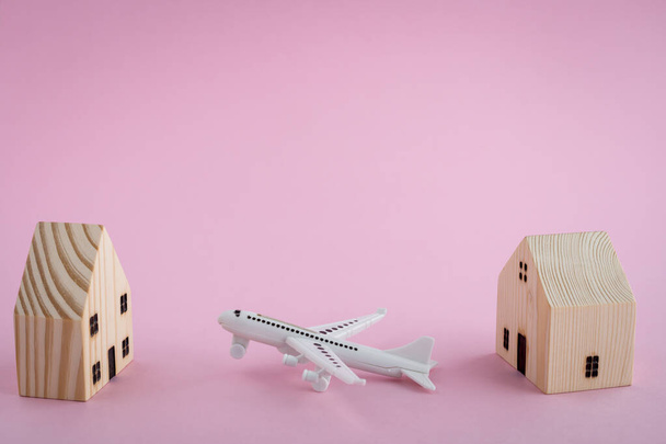 White airplane and wooden house model on pink background for travel concept - Fotó, kép