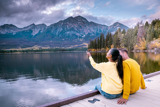 Çiftler göl kenarında gün batımını izliyor, Alberta Kanada 'da sonbahar boyunca Jasper Piramidi, günbatımında göl kenarına düşen renkler, Jasper Piramidi. - Fotoğraf, Görsel