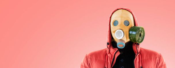 man in a yellow gas mask and a hood on a pink background - Fotoğraf, Görsel