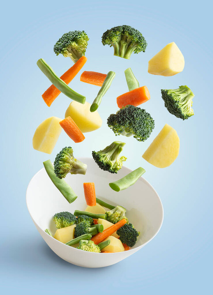 Mavi arka planda uçan sebzeler, yeşil fasulye, brokoli, patates, havuç - Fotoğraf, Görsel