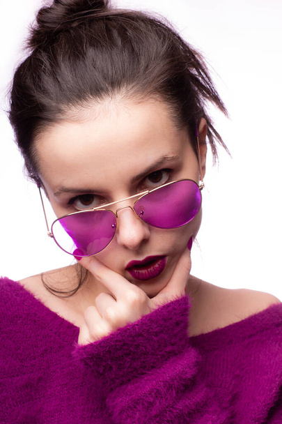 girl in a purple sweater, purple glasses with purple lipstick on her lips - Fotó, kép