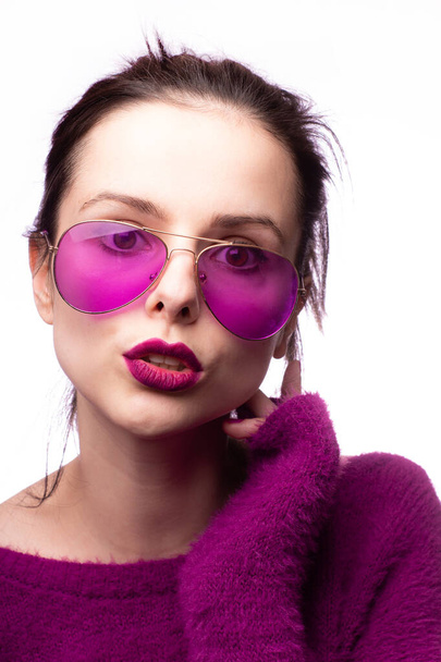 girl in a purple sweater, purple glasses with purple lipstick on her lips - Фото, изображение