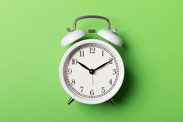 White vintage alarm clock on green background - Fotó, kép