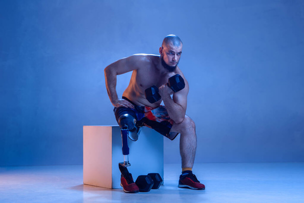 Athlete disabled amputee isolated on blue studio background - Foto, Bild