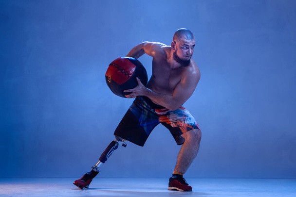 Athlete disabled amputee isolated on blue studio background - Fotoğraf, Görsel