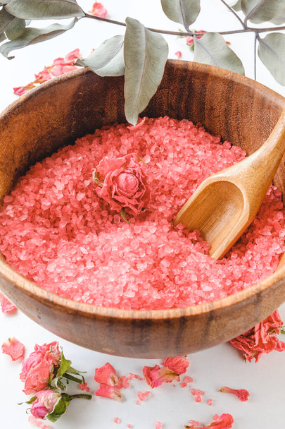 Деревянная чаша с морской солью с экстрактом и запахом роз, сушеные бутоны роз на заднем плане
 - Фото, изображение