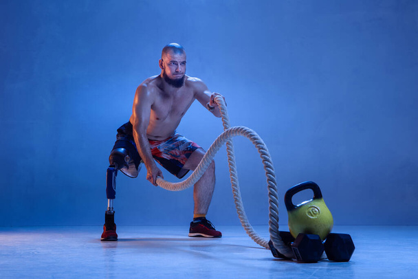 Athlete disabled amputee isolated on blue studio background - Фото, изображение