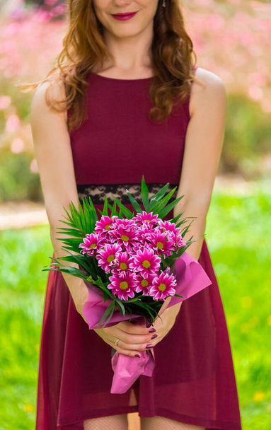 Woman holding a bouquet. She is wearing a purple dress. - Photo, Image