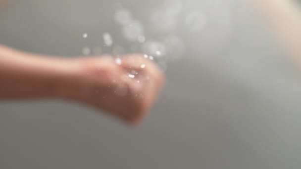 BOTTOM UP: Person zerkleinert Salz in ihrer Hand und streut es über die Kamera. - Filmmaterial, Video