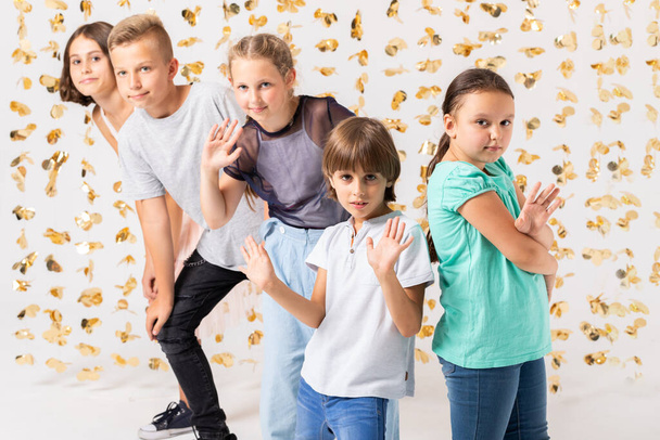 Room decorated with golden decorations and group of cool kids fooling around and making funny poses - 写真・画像