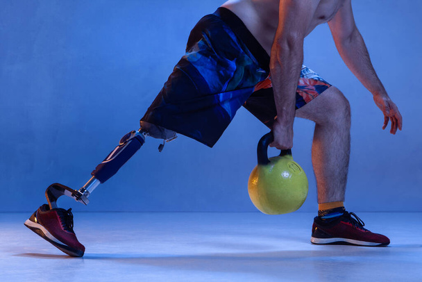 Athlete disabled amputee isolated on blue studio background - Fotó, kép