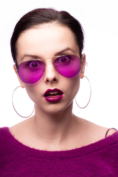 girl in a purple sweater, purple glasses with purple lipstick on her lips - Foto, afbeelding