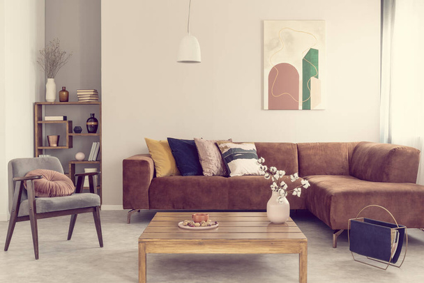 Удобный коричневый бархатный диван с подушками в элегантном интерьере гостиной
 - Фото, изображение