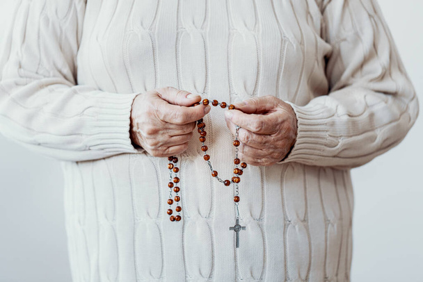 Close-up of a senior hands holding a rosary - Foto, imagen