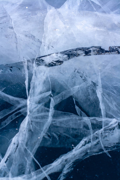 Textura natural de un lago de invierno con grietas en hielo transparente. Hielo azul grueso. Vertical
. - Foto, Imagen