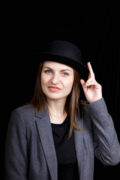 linda chica joven en sombrero y chaqueta gris sobre fondo negro
 - Foto, Imagen