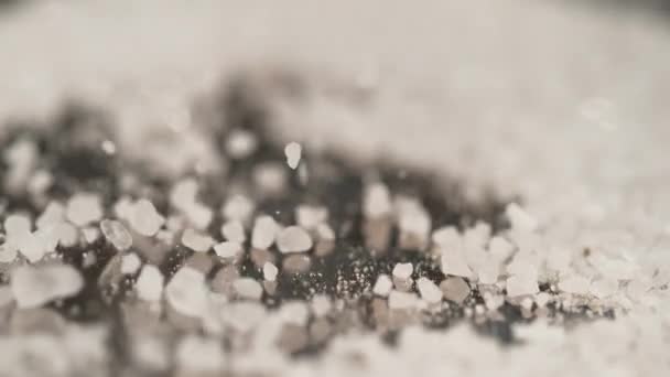 MACRO, DOF: Witte suiker wordt over het granieten aanrecht gestrooid. - Video