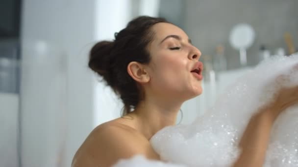 Closeup hot woman blowing foam at bathtub. Sexy girl playing with bubbles - Felvétel, videó