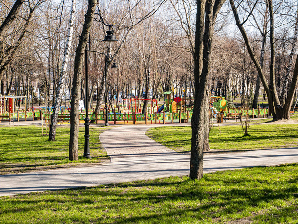 Детская площадка в весеннем общественном парке на солнце. Фоновое изображение. Место для смс. Инфраструктура
. - Фото, изображение