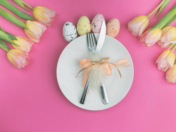 Belle impostazioni di posate da tavola pasquali di lusso come coltello, forchetta con cornice di tulipani colorati sulla superficie rosa. Sfondo vacanza, biglietto di auguri, primo piano
 - Foto, immagini