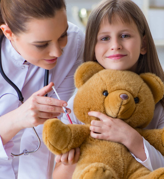 Woman female doctor examining little cute girl with toy bear - Foto, imagen